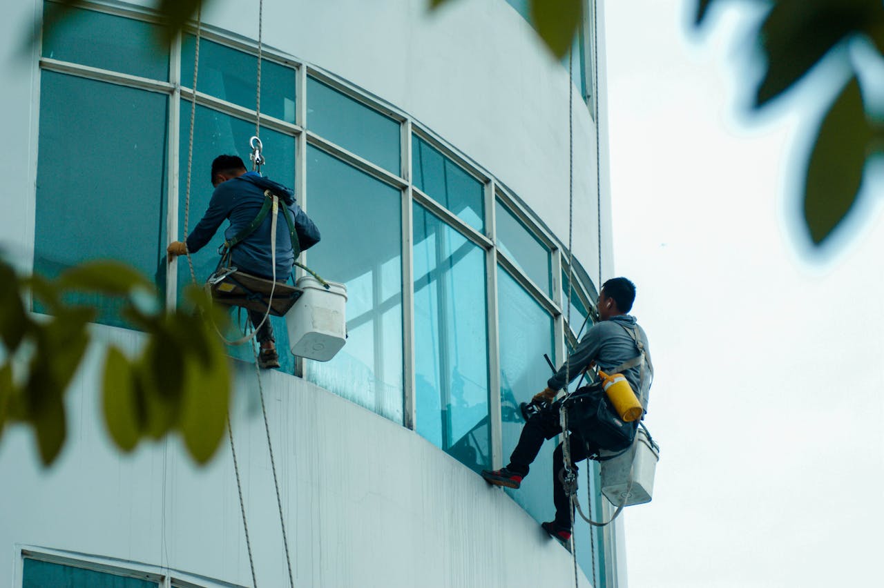 services-img Window cleaners suspended on ropes clean a high-rise building's glass exterior.